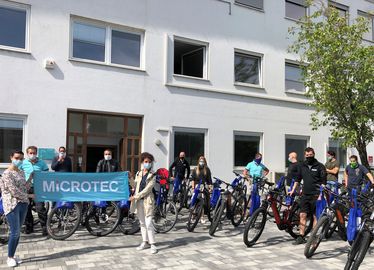 Gruppo di dipendenti Mircotec insieme alle loro e-bike in prestito, davanti alla sede dell'azienda.